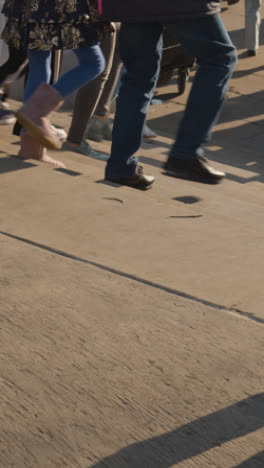 Vertical-Video-Close-Up-Of-Feet-Walking-Up-Steps-In-Busy-City